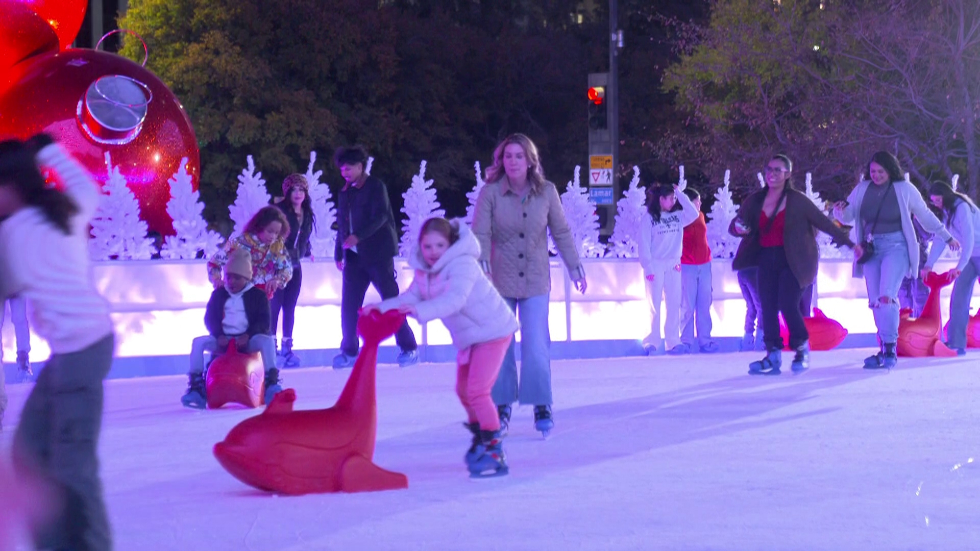 Kids learning to skate with red seal skate aids at a public skating session