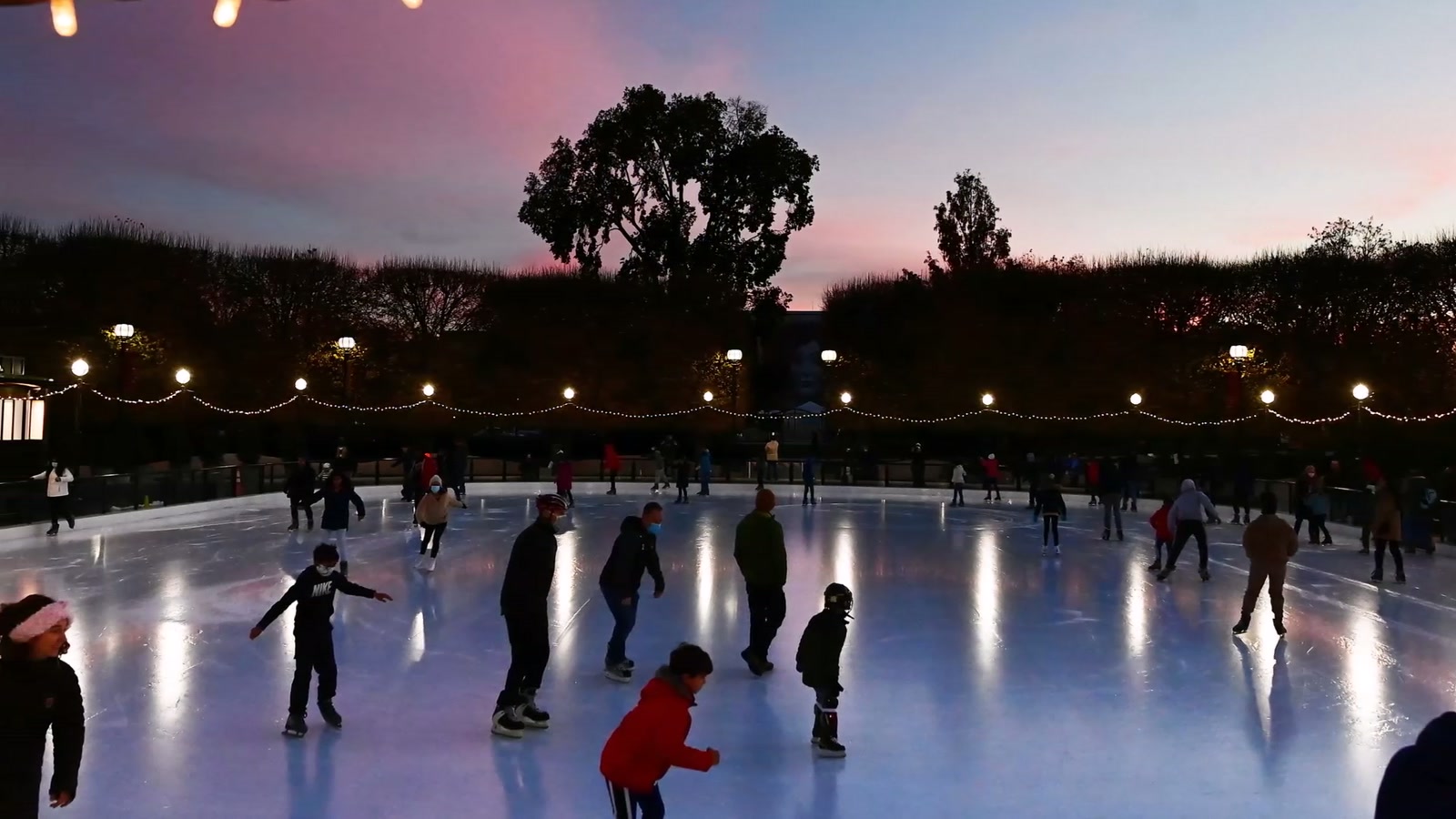 Skaters on the Chillville mobile rink at dusk with palm trees behind